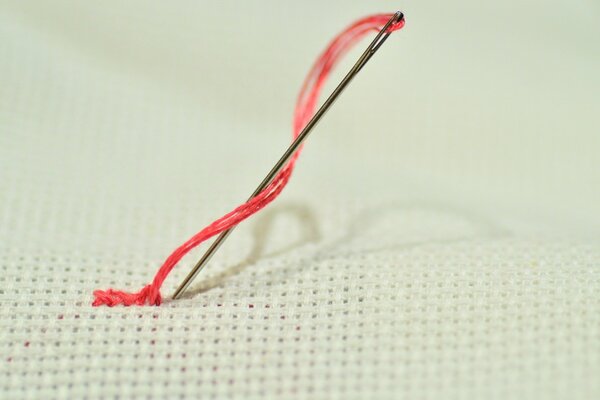 Thread with a needle on the canvas. Macro photography