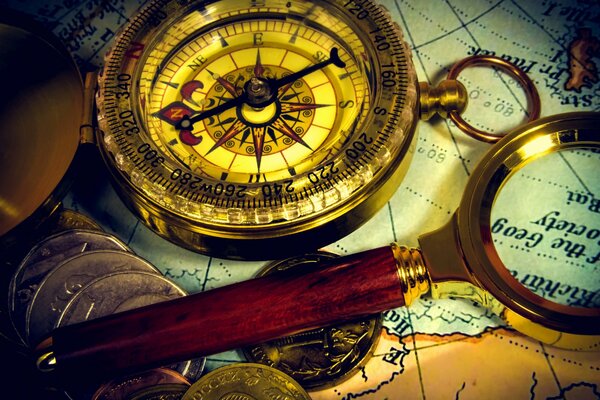 Compass, magnifying glass and coins on the traveler s map