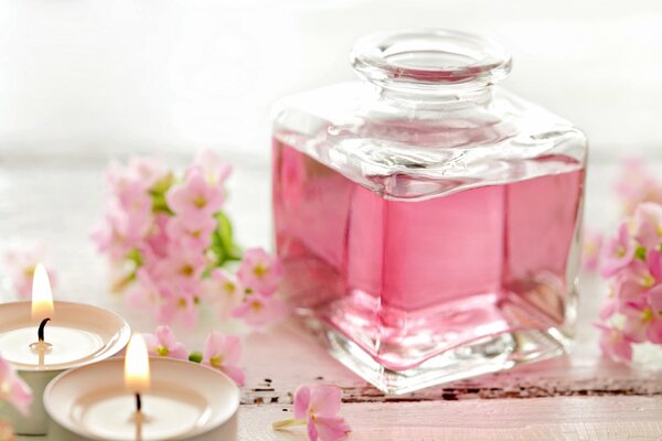 Pink perfume in a bottle and candles