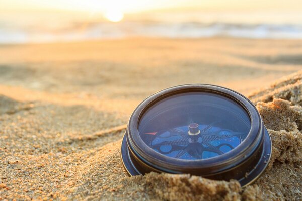 Compass in the sand in the morning light of the sun