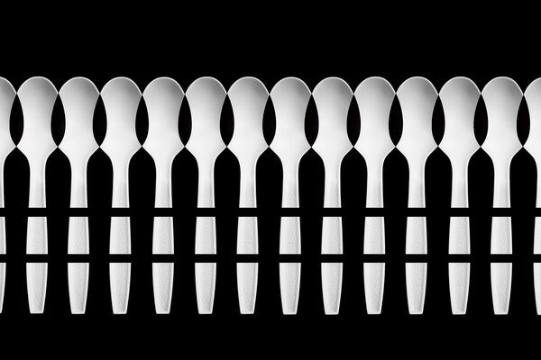 Interesting chiaroscuro pattern of spoons on a black background