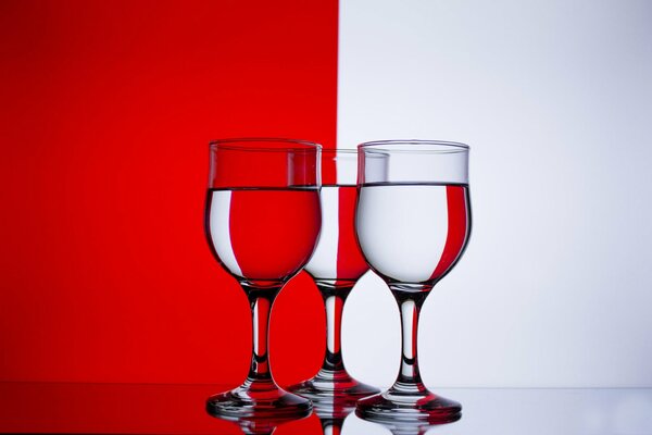 Bicchieri di vino con acqua su sfondo rosso e bianco