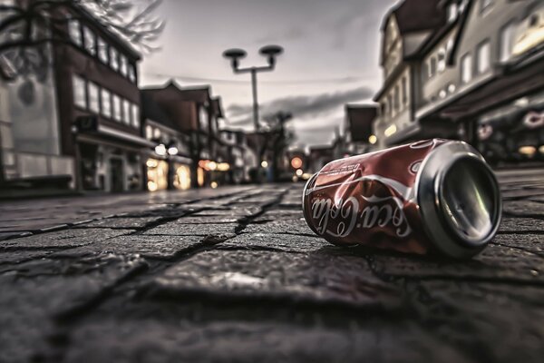 Pot vide de Coca-Cola sur fond de trottoir