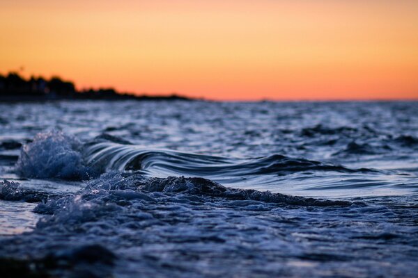 Olas de la tarde en el fondo de la puesta de sol