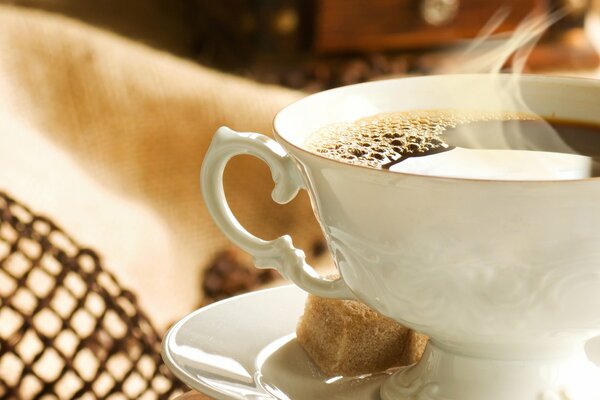 A cup of coffee with sugar on a saucer