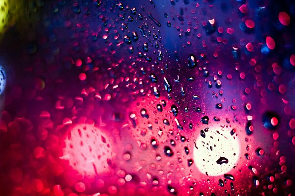 Gotas de lluvia en el cristal de la ciudad de la noche