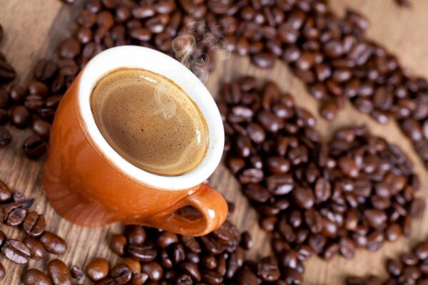 A cup of hot coffee on the background of a heart of coffee beans