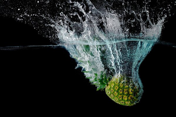 Spritzer von Ananas, die ins Wasser gefallen ist