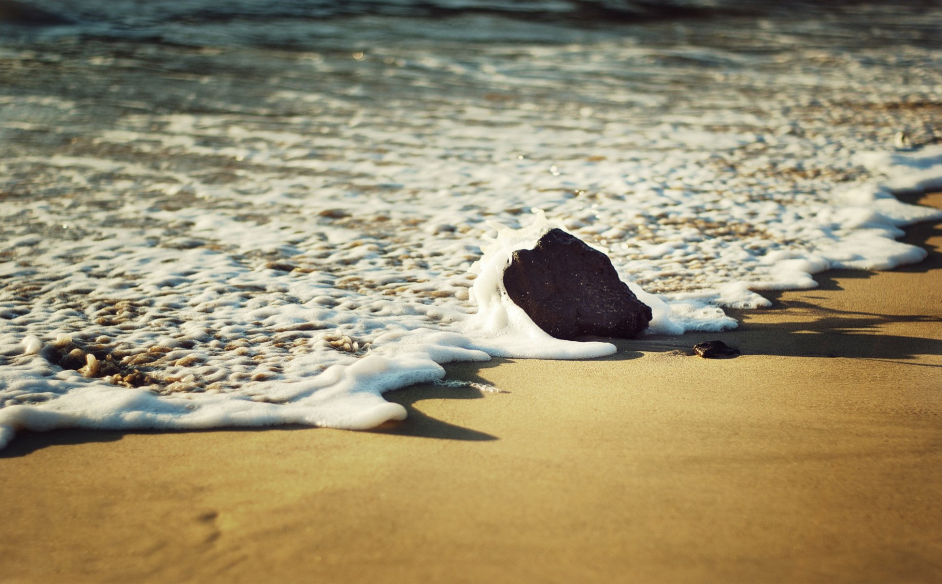 close up sea foam beach sand stone