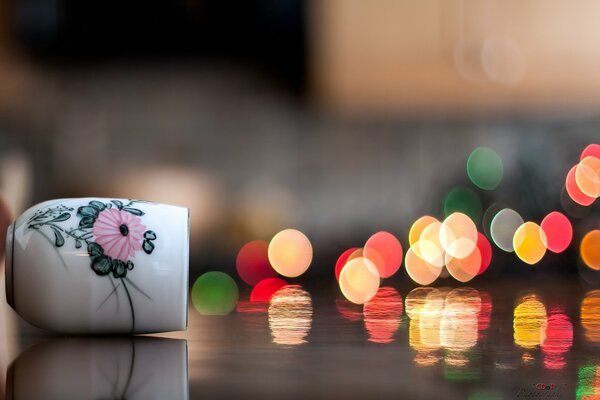 The illusion of a cup in macro with multicolored light balls