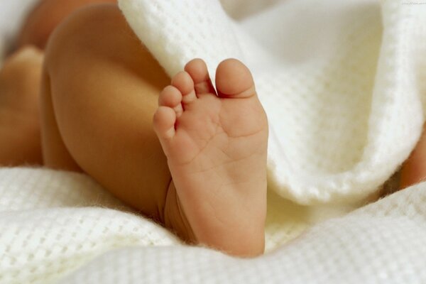 La jambe du bébé est visible sous la couverture