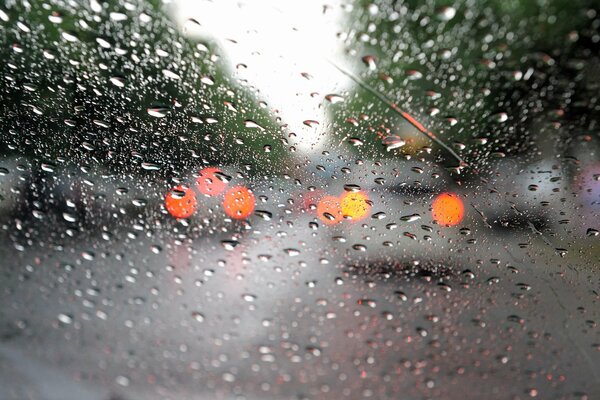 Macro shot of drops on the car window, headlights