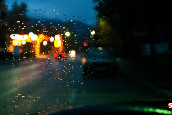 Pluie dans la rue derrière le pare-brise de la voiture