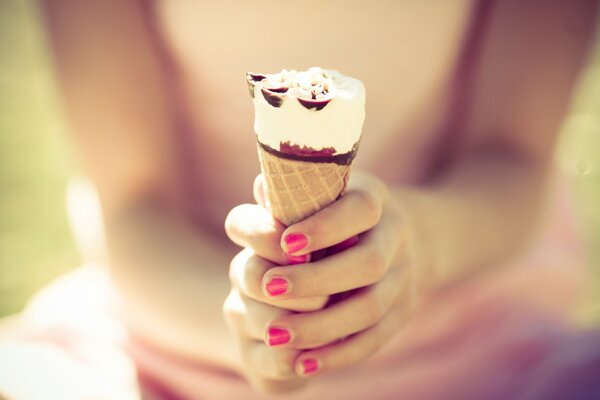 Chica con manicura brillante sostiene helado