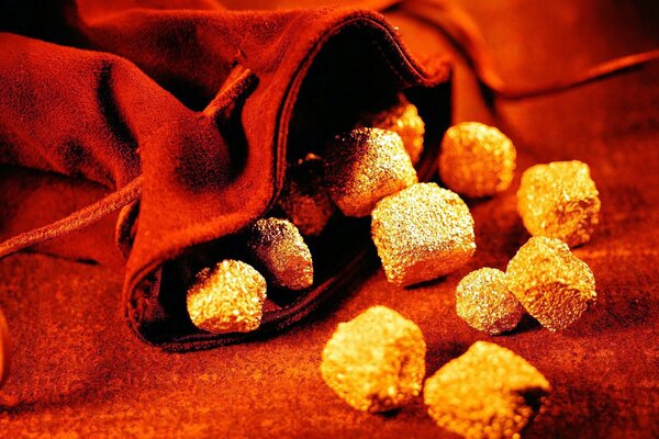 A scattering of gold stones from a red bag