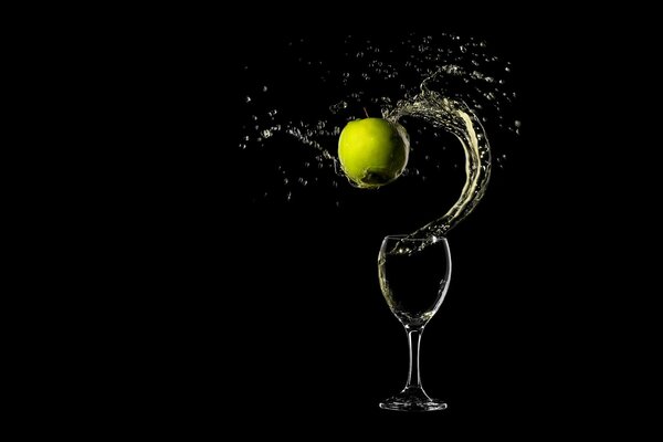 An apple falling into a glass of water