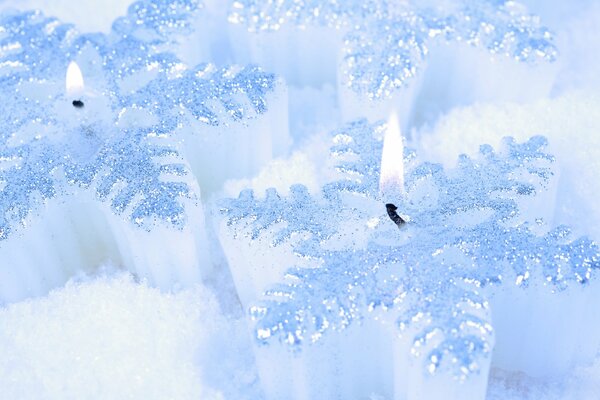 Beautiful white candles on white snow one