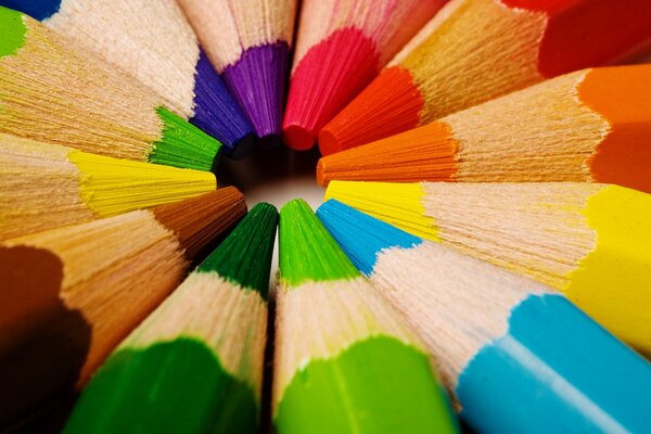 Twelve colored pencils lie in a circle, touching each other with the pencils