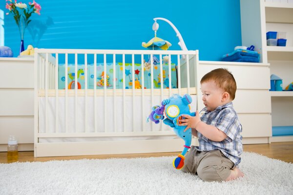 Petit garçon sur un tapis blanc avec un éléphant dans les mains