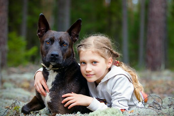 Mädchen umarmt mit Hund im Wald