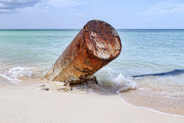 Tubo di metallo che sporge dalla sabbia sul mare