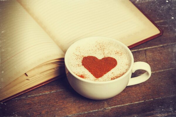 A cup of coffee with a heart pattern and a diary