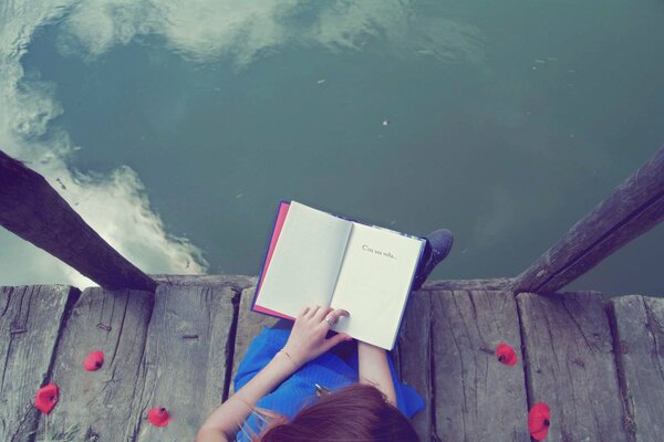 A girl in a blue dress reads a book