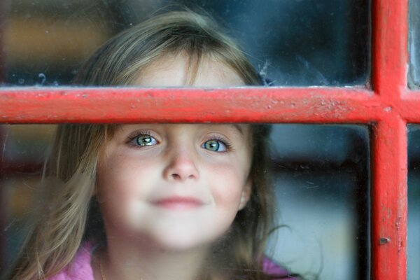 Chica fuera de la ventana con rejilla roja