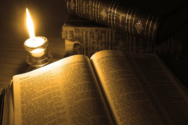 The fire from the candle illuminates the pages of the book