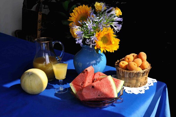 Natura morta sul tavolo bouquet in vaso, anguria, melone e brocca con succo