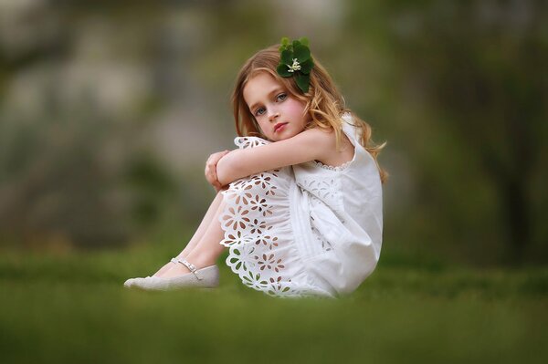 A girl in a white dress with a hairpin on the grass