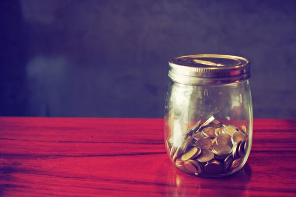 Hucha con monedas en la mesa roja
