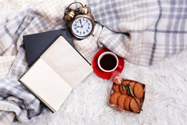 Le réveil se trouve sur un plaid à côté d un livre et d un café