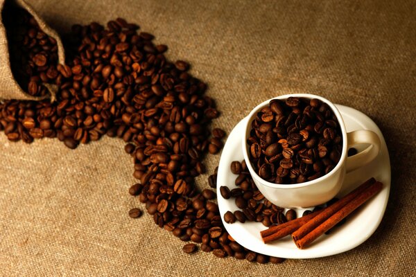 Immagine di chicchi di caffè con tazza e cannella su sfondo marrone