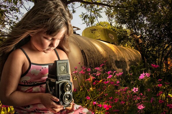 Una niña con una cámara en el fondo de un Prado de flores y una cisterna