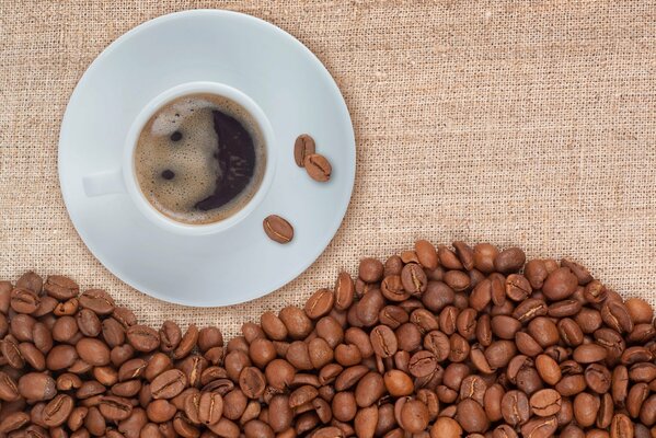 Taza de café en platillo y granos de café