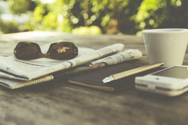 Zeitung Kaffee und Gläser mit Smartphone am Boden des Tisches