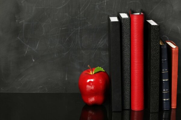 Agenda rouge et noir sur fond noir. pomme rouge sur une étagère noire