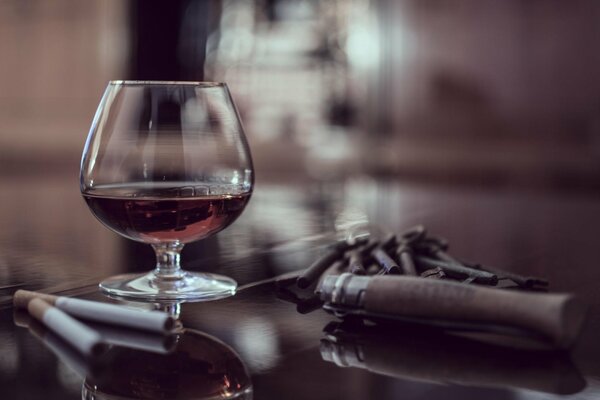 Una Copa de coñac sobre una mesa con cigarros