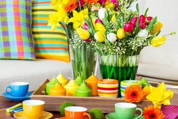 Arrangement coloré de tasses et de bougies colorées sur la table avec des tulipes et des serviettes