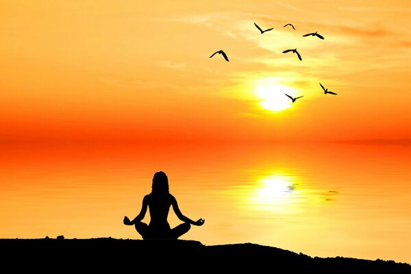Hombre meditando en el sol en la orilla del mar