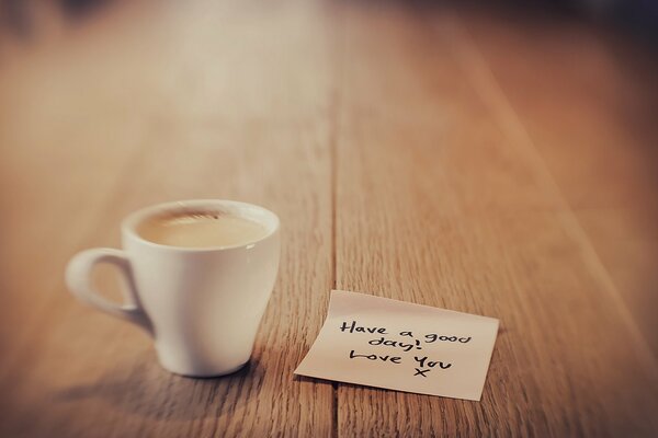 Tasse de café sur la table avec une Note à côté