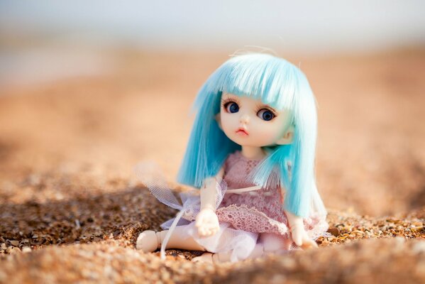 Poupée assise sur le sable avec des mouches bleues