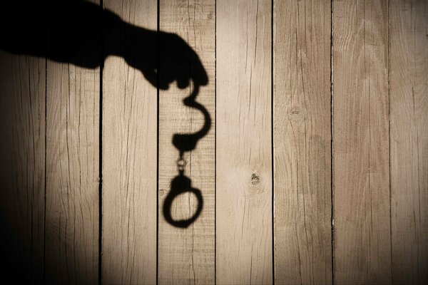 Shadow of a hand with handcuffs on the boards