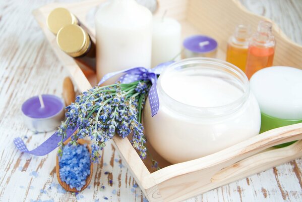 A branch of lavender tied with a ribbon lying between candles next to a spoonful of sea salt for a bath