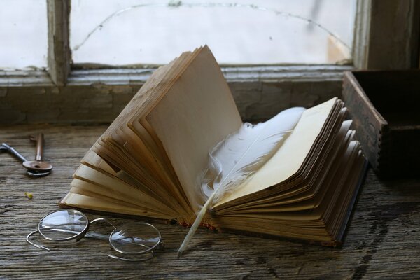 Glasses are lying on the windowsill near a book with a white pen