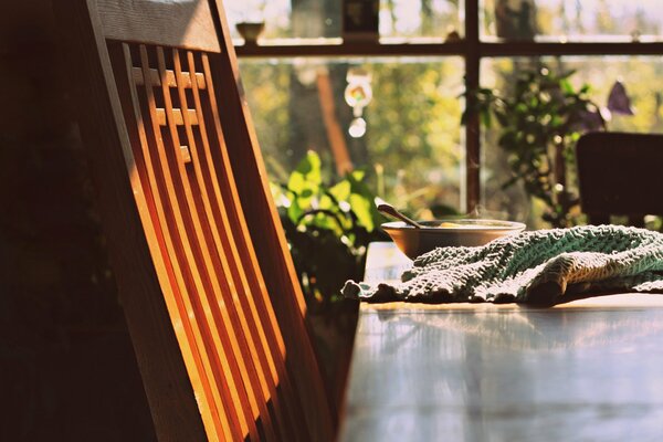 A wooden chair next to the table where breakfast is served in the rays of the rising sun