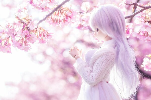 A toy doll. a girl with long lilac hair on a background of cherry blossoms