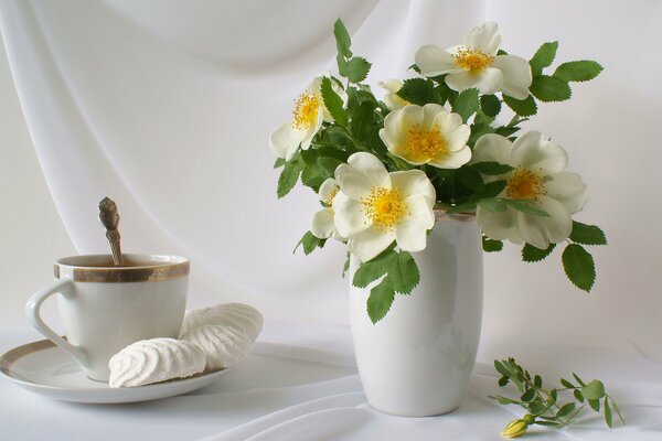 Still-life. a vase with flowers and tea in a cup and saucer