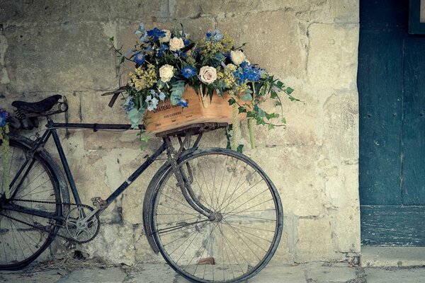 Ein Fahrrad mit Blumen, das neben einer Wand steht